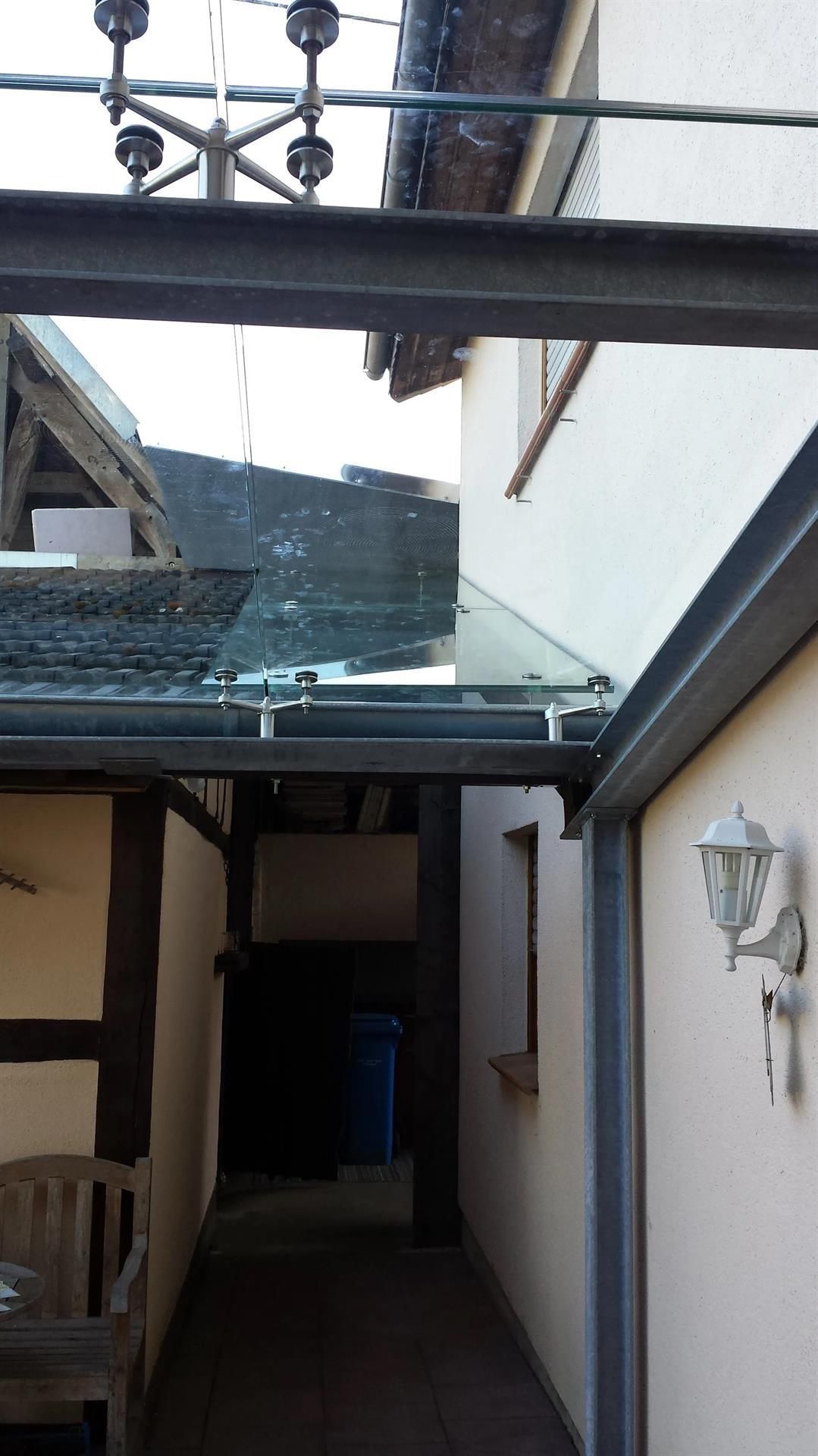 Ein schmaler Flur zwischen zwei Gebäuden mit einem Glasdach