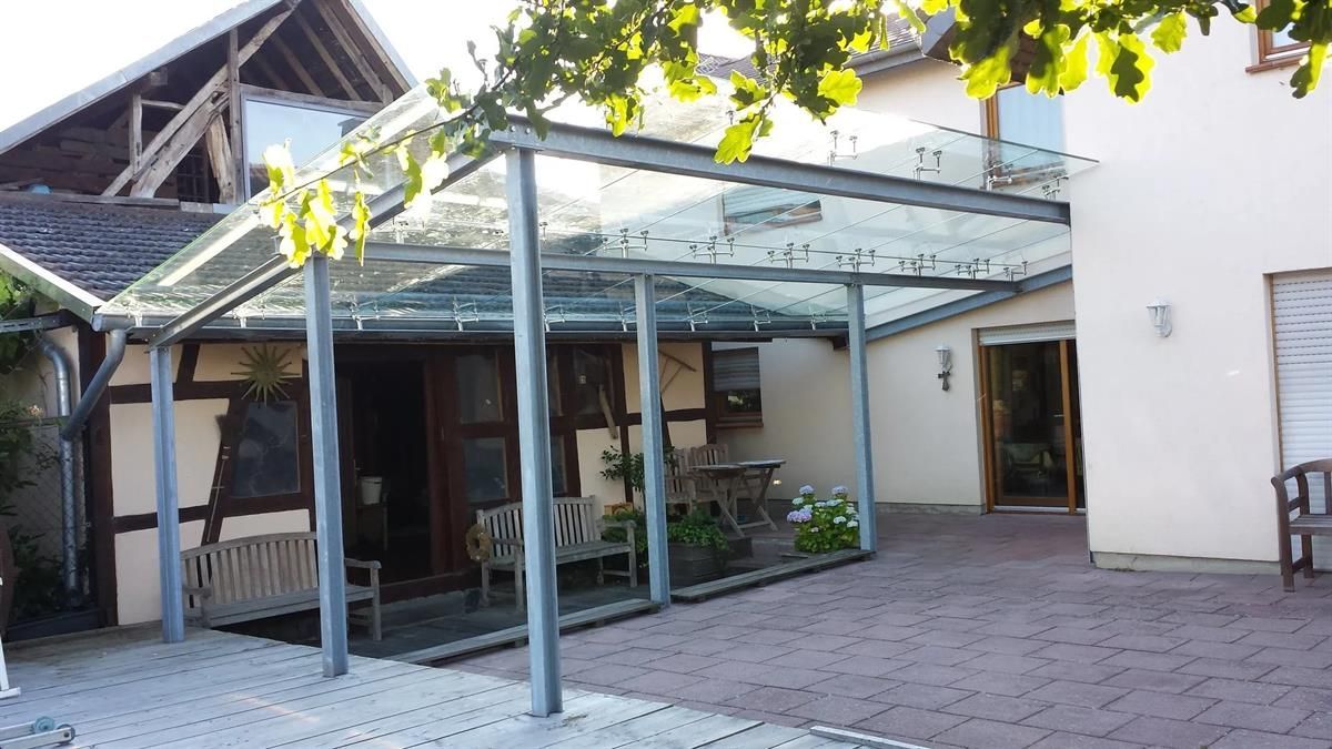 Ein Haus mit einer glasüberdachten Veranda und einer Bank