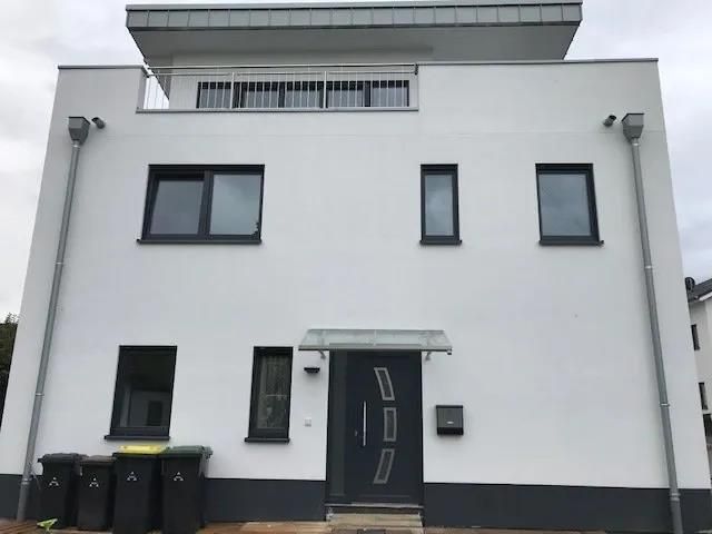 Ein weißes Gebäude mit schwarzen Fenstern und einer schwarzen Tür