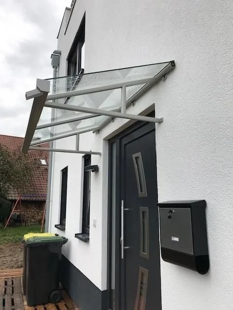 Ein weißes Haus mit einer schwarzen Tür und einem Glasdach über der Tür.