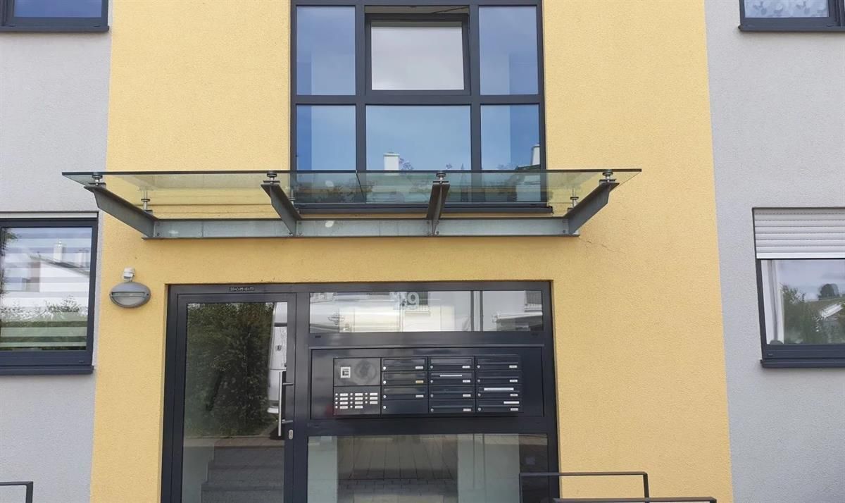 Ein gelbes Gebäude mit einer schwarzen Tür und einem Glasdach