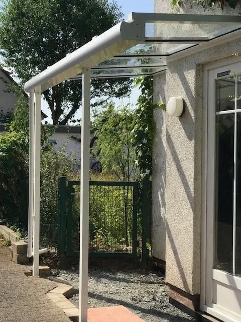 Ein weißes Haus mit einem Glasdach über der Tür