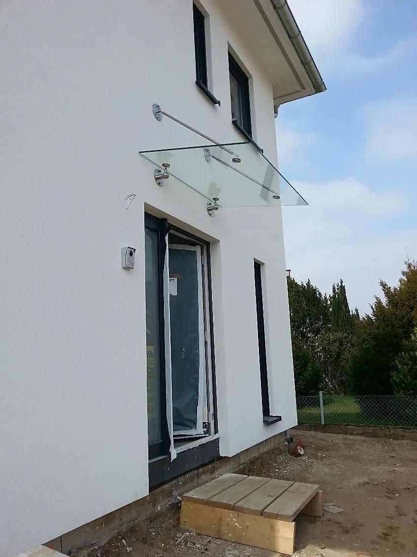 Ein weißes Haus mit einem Glasdach über der Tür.