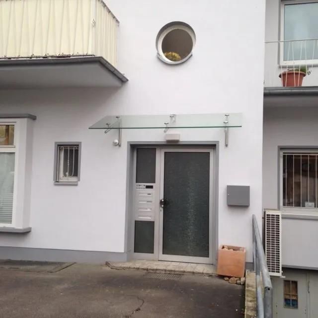 Ein weißes Gebäude mit einem Glasdach über der Tür