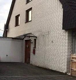 Ein weißes Backsteinhaus mit Garage und Einfahrt.