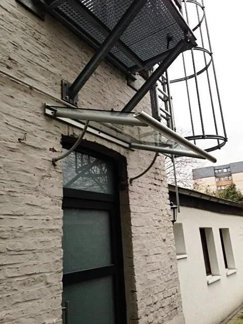 Ein weißes Backsteingebäude mit einem Glasdach über einer Tür.