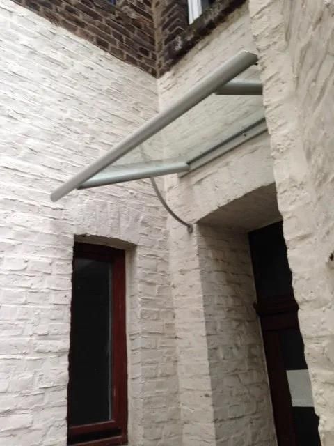 Ein weißes Backsteingebäude mit einem Glasdach über der Tür