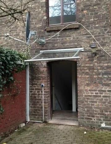 Ein Backsteingebäude mit einem Vordach über der Tür und einem Fenster.