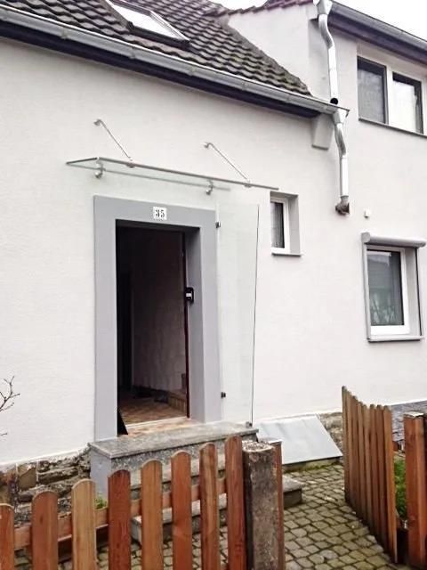 Ein weißes Haus mit einem Holzzaun davor.