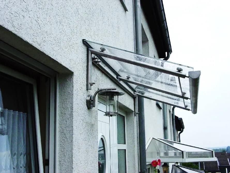 Ein weißes Gebäude mit einem durchsichtigen Vordach über der Tür