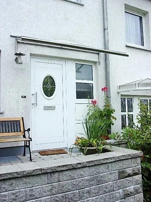 Eine weiße Tür mit einem runden Fenster und einer Bank davor