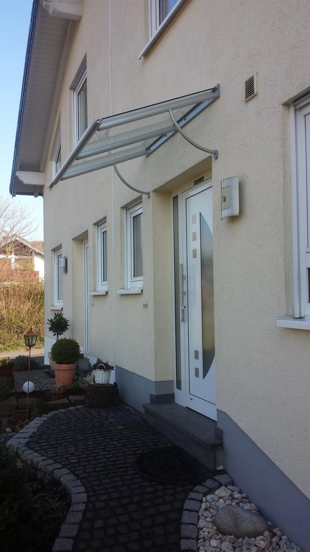 Ein weißes Haus mit einem Glasdach über der Tür