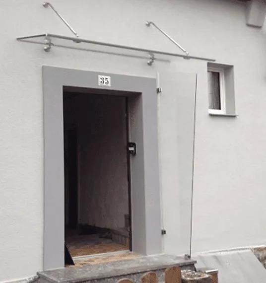 Eine Tür mit einem Glasdach darüber und einem Fenster an der Seite eines Gebäudes.