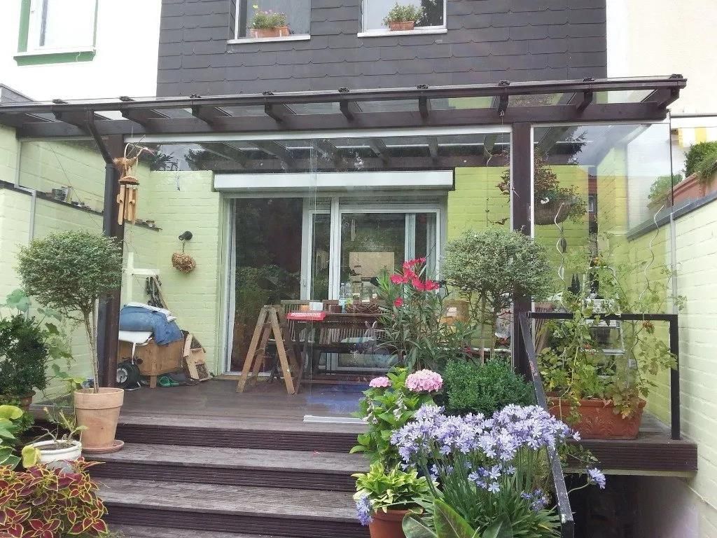 Ein Haus mit einer Treppe, die zu einer Terrasse mit Blumen und Topfpflanzen führt
