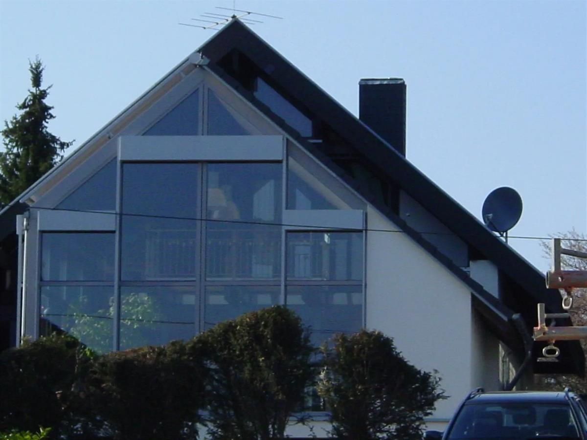 Ein Auto steht vor einem Haus mit vielen Fenstern