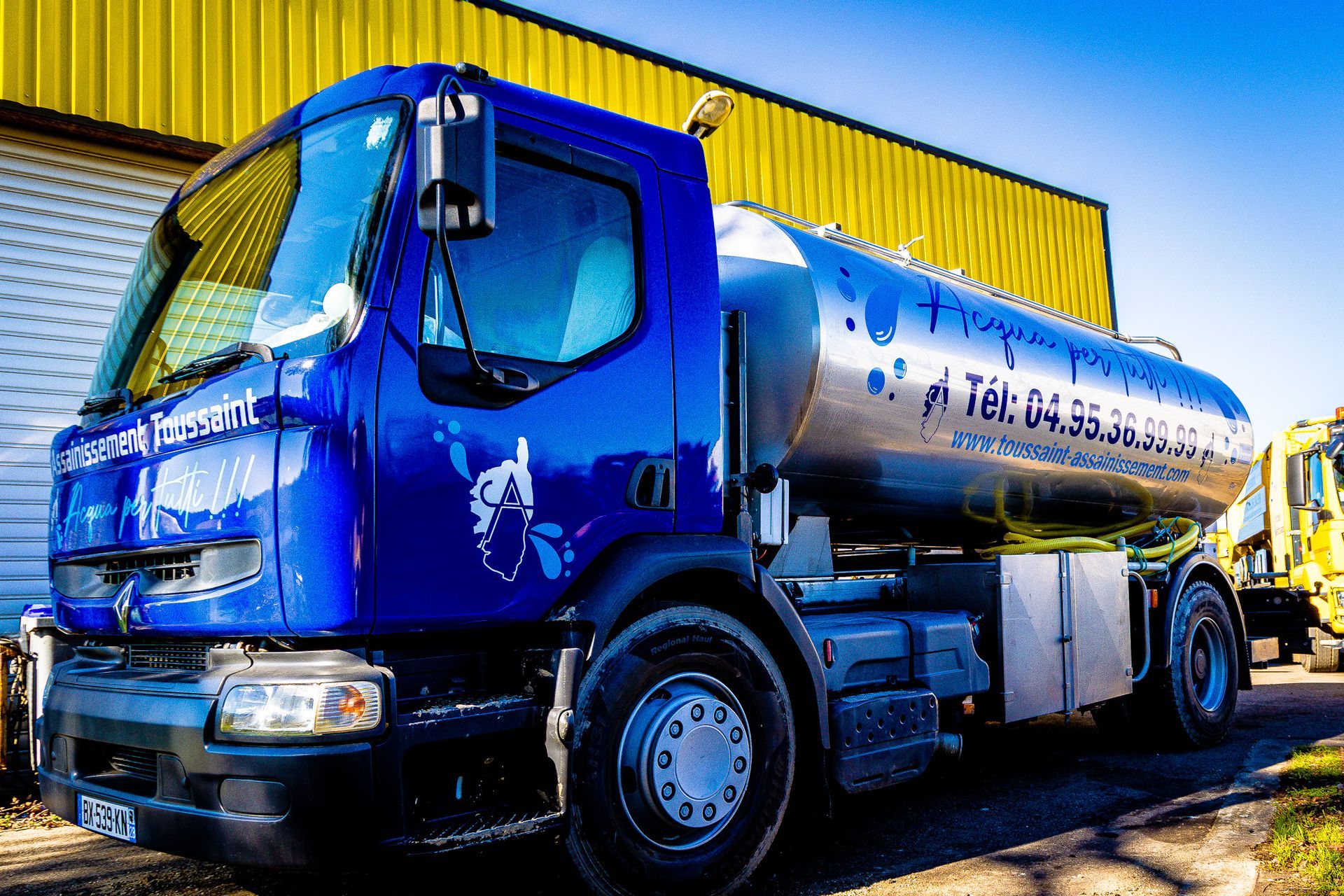 Un camion bleu et un hangar jaune.