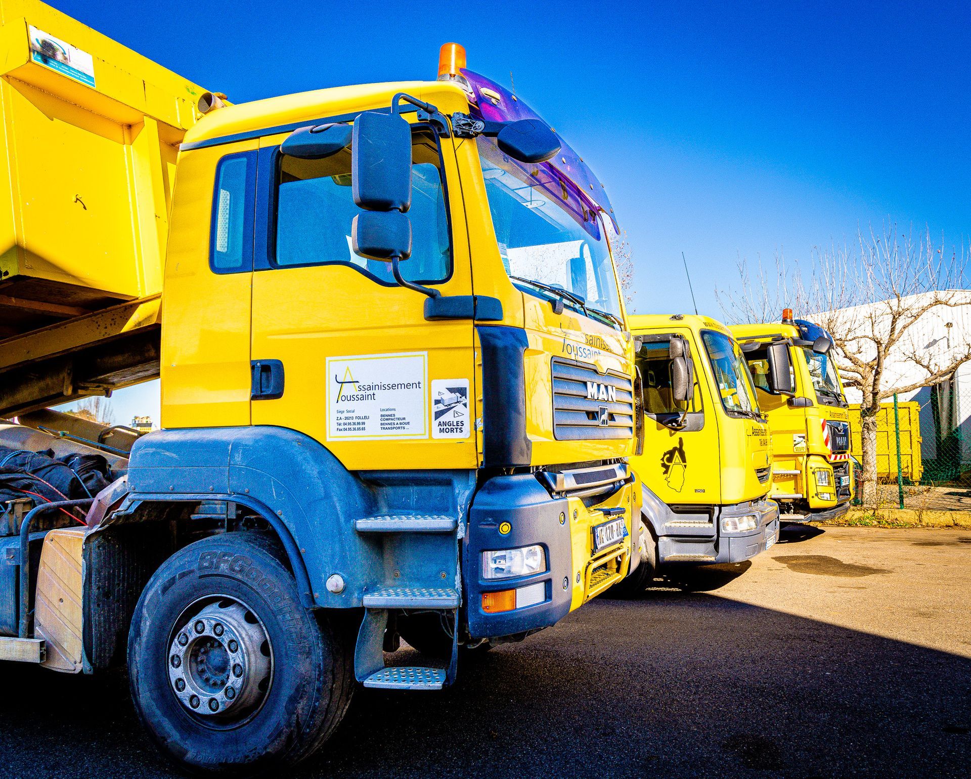 Trois camions jaunes de profil.