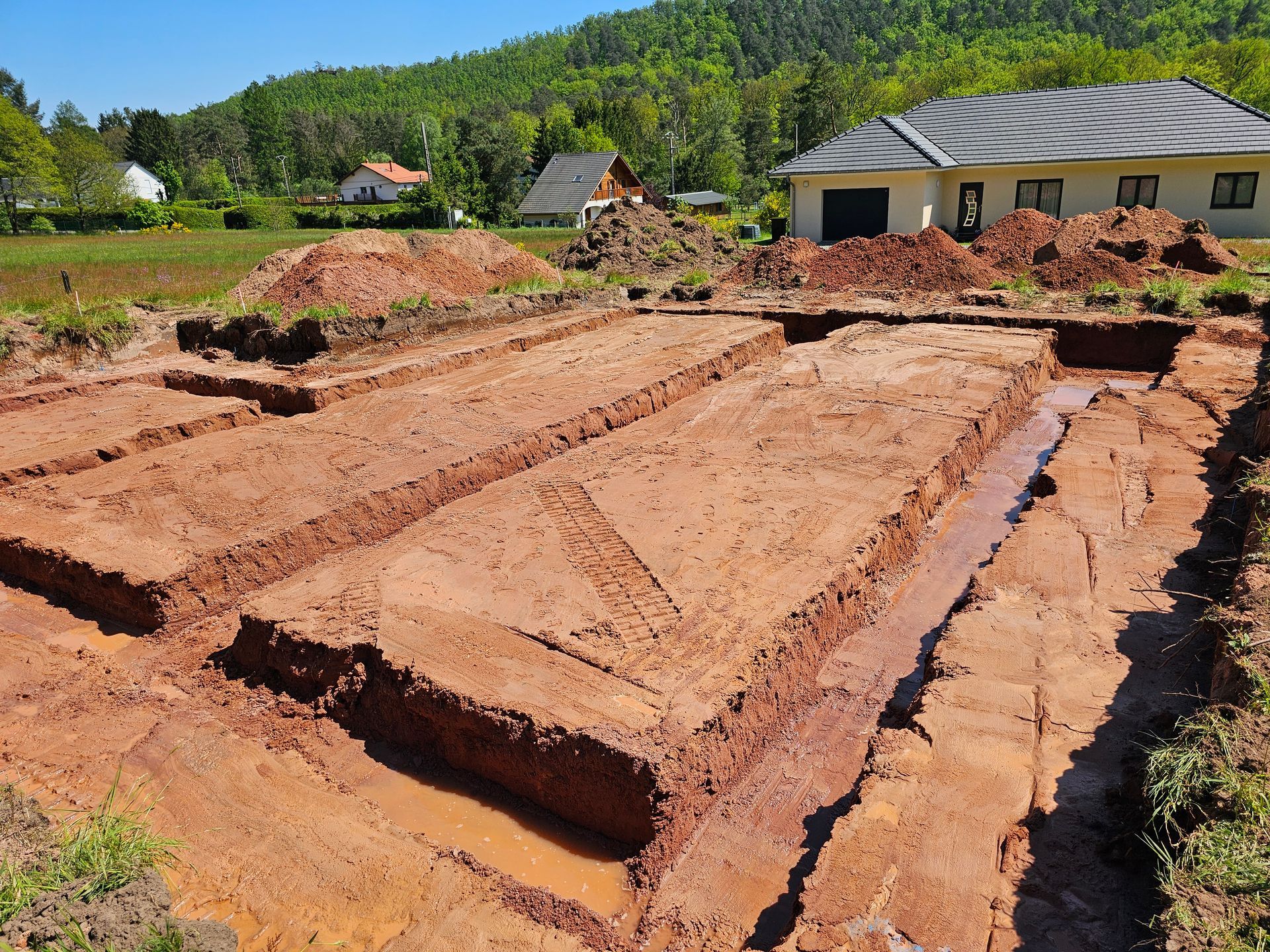Terrain vague excavé avec des tranchées et des monticules de terre sous un ciel dégagé.