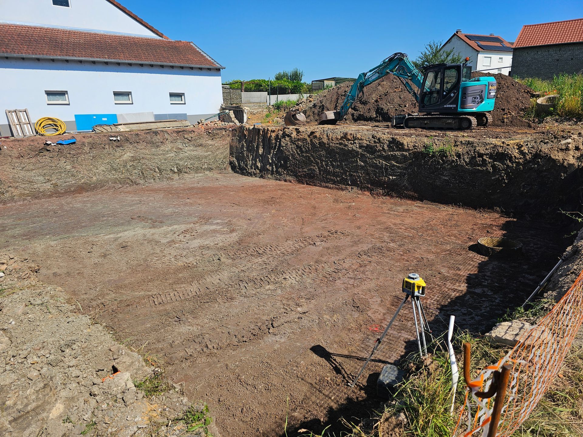 Excavation rectangulaire d'un jardin avec des murets de terre dans une cour arrière ensoleillée.