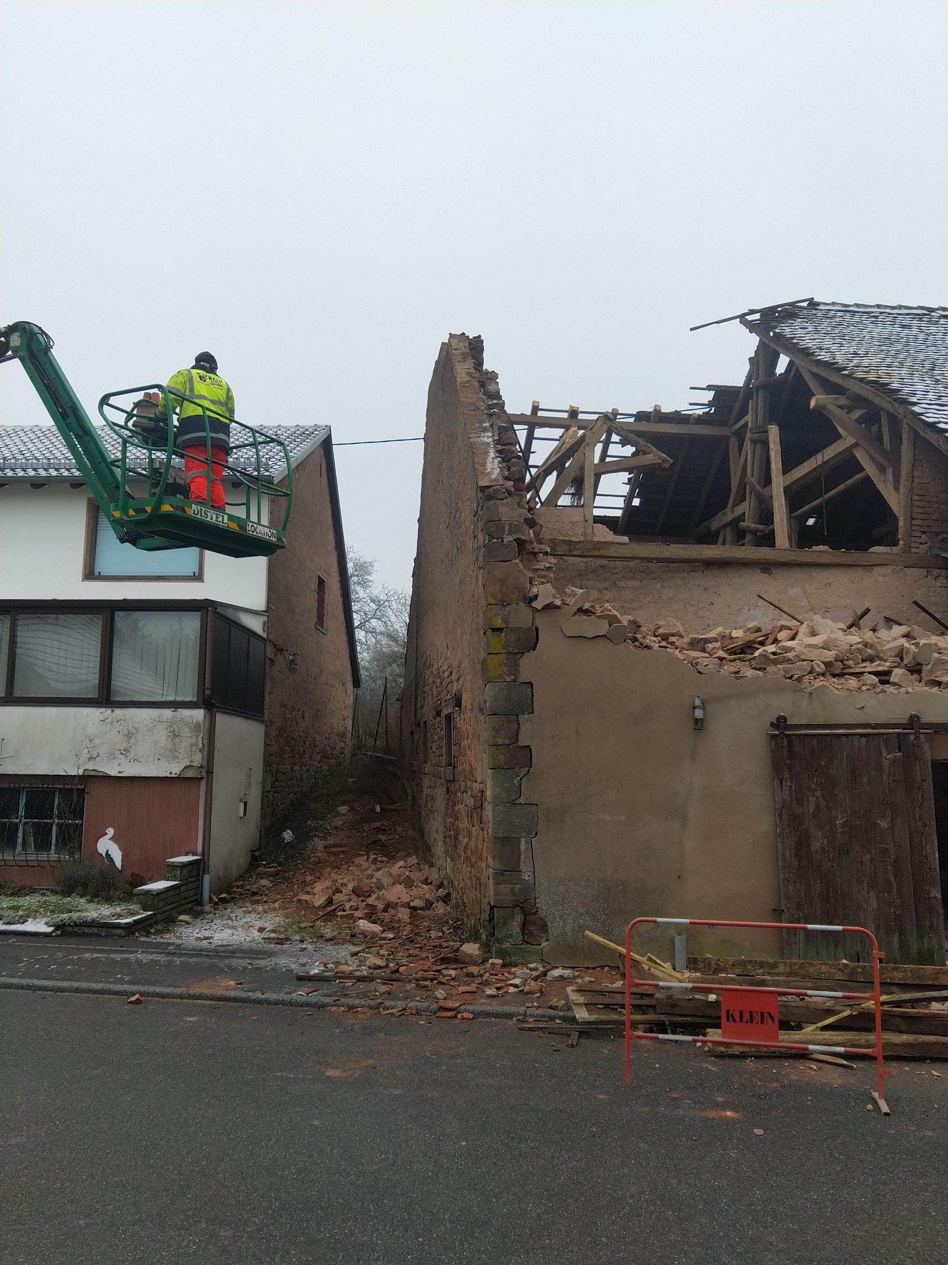Des professionnels sur une échelle à côté d'un bâtiment partiellement démoli.