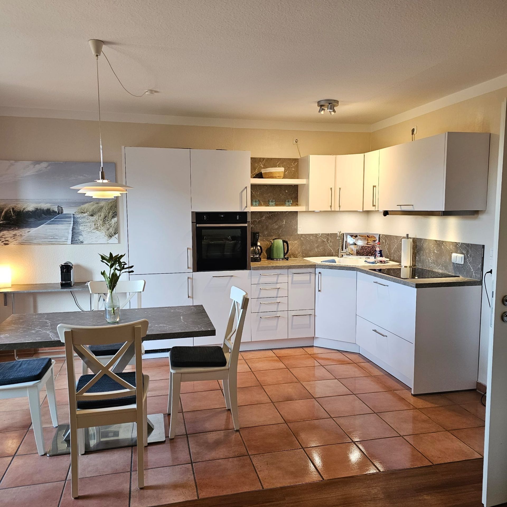 Eine Küche mit weißen Schränken und einem Tisch und Stühlen