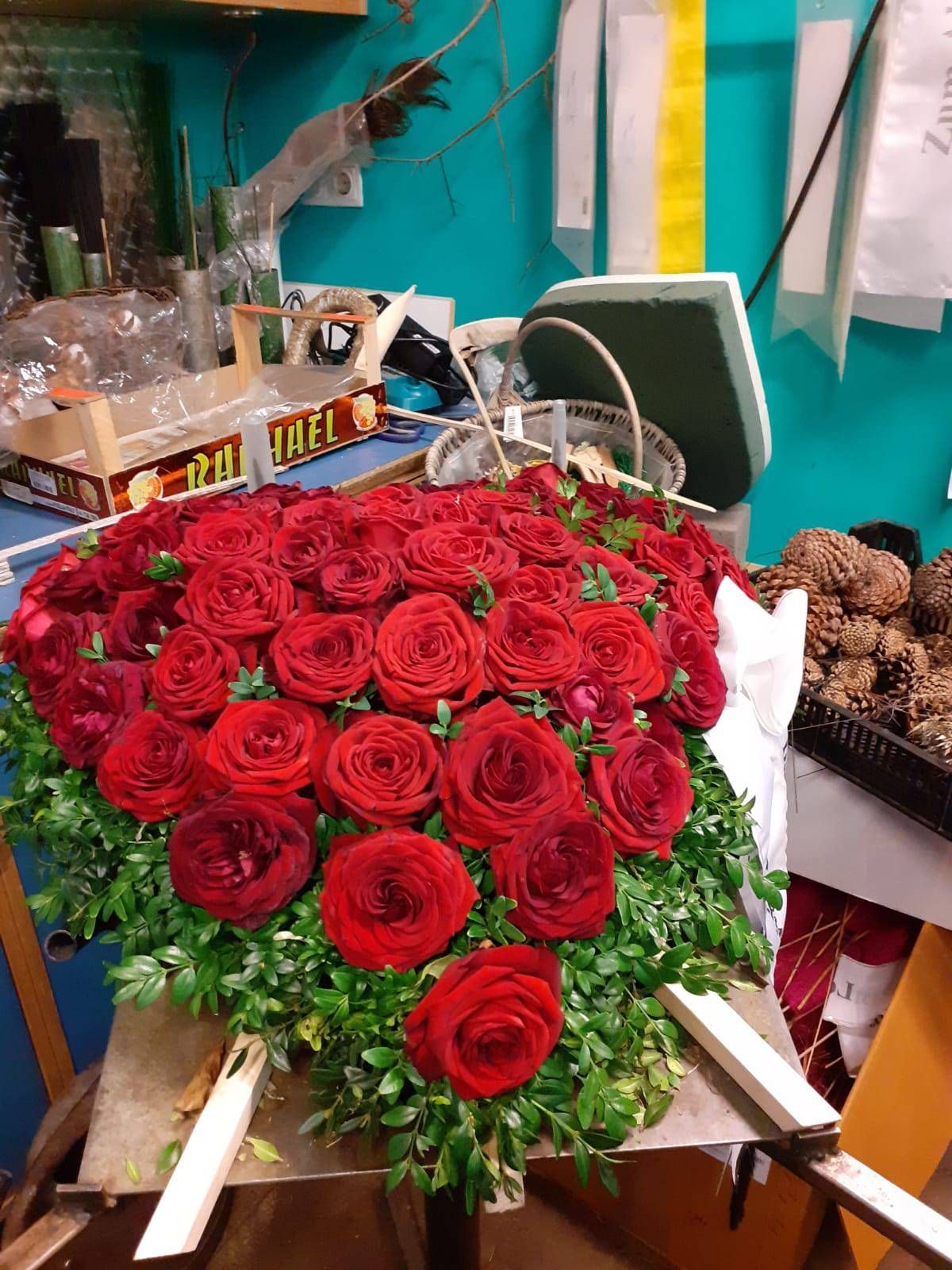 Rote Rosen, in Herzform auf einem Tisch in einem Blumengeschäft arrangiert.