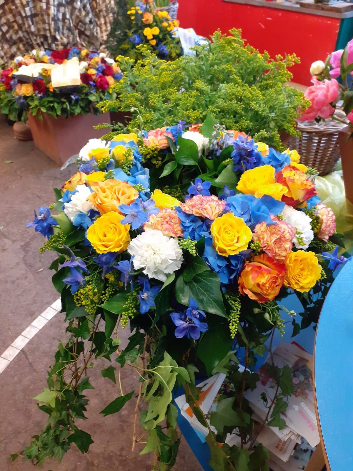Farbenfroher Blumenkranz mit gelben, blauen und orangen Blumen.