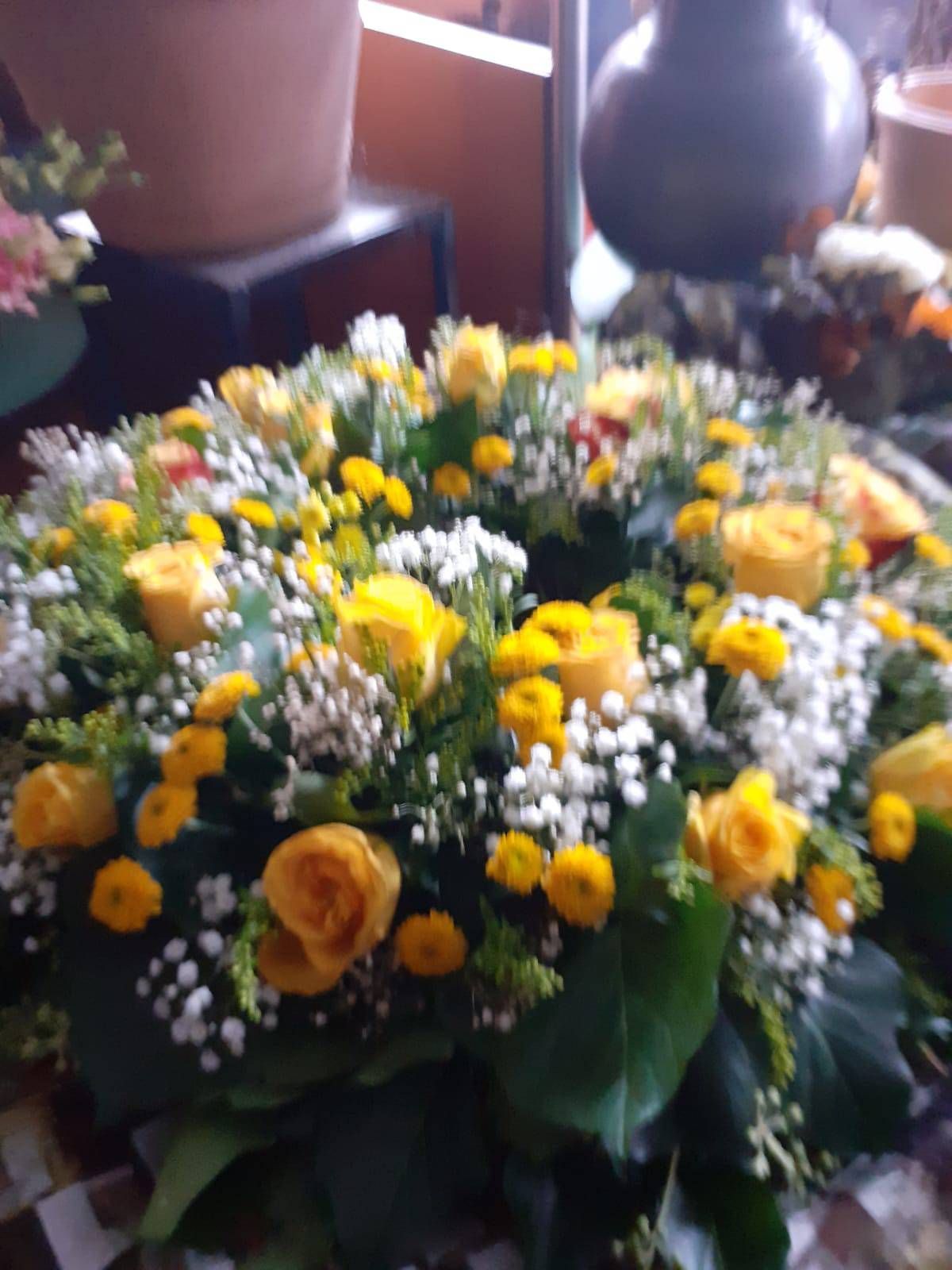 Blumenkranz aus gelben Rosen und Schleierkraut.