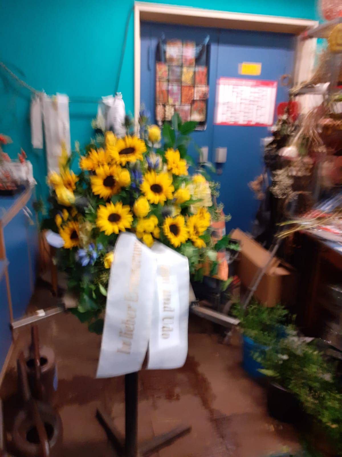 Sonnenblumenarrangement mit weißem Band, drinnen.