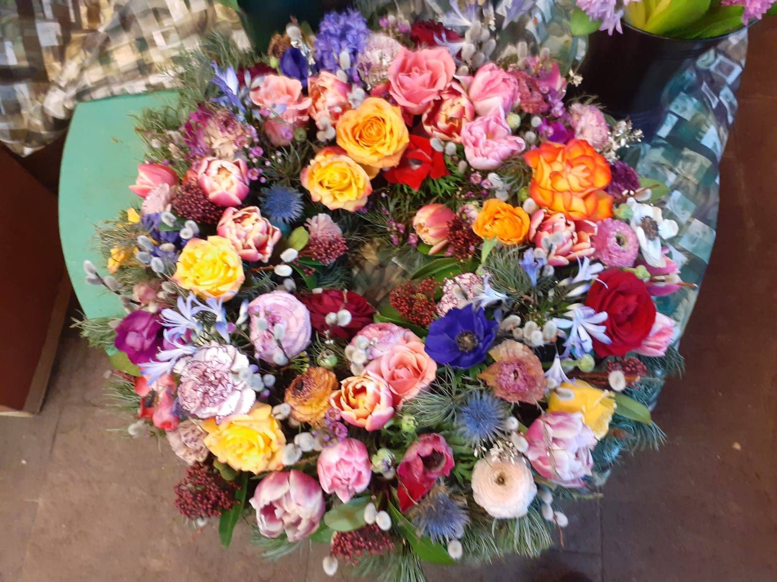 Farbenfroher Blumenkranz mit Rosen und verschiedenen Blüten.