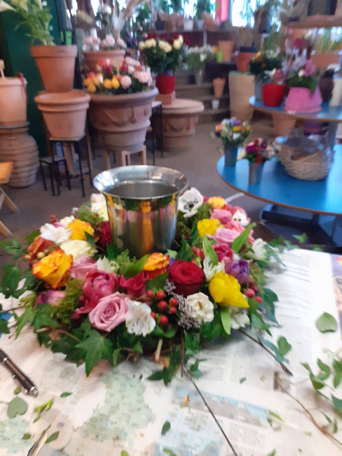 Blumenkranz mit bunten Blüten und Metalleimer in einem Blumenladen.