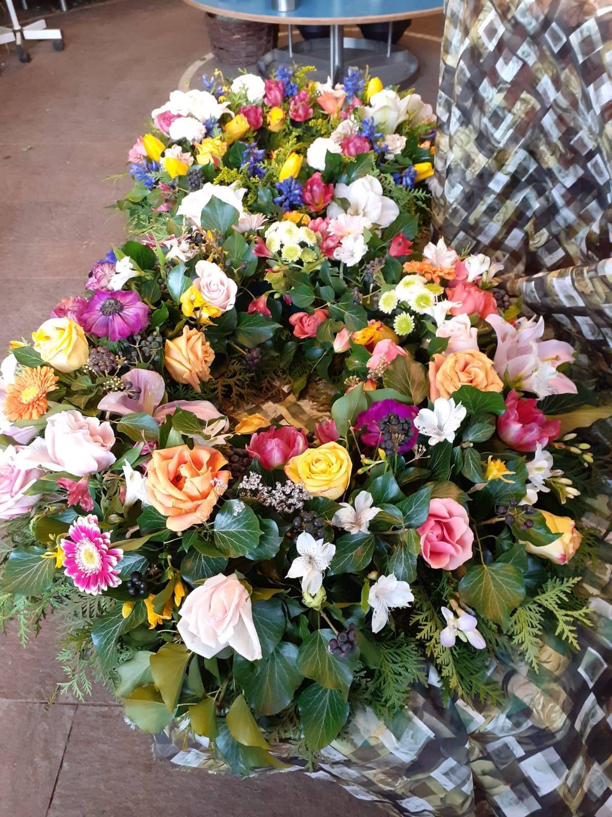 Farbenfrohes Blumenarrangement mit einer Vielzahl von Blumen, darunter Rosen und Lilien.
