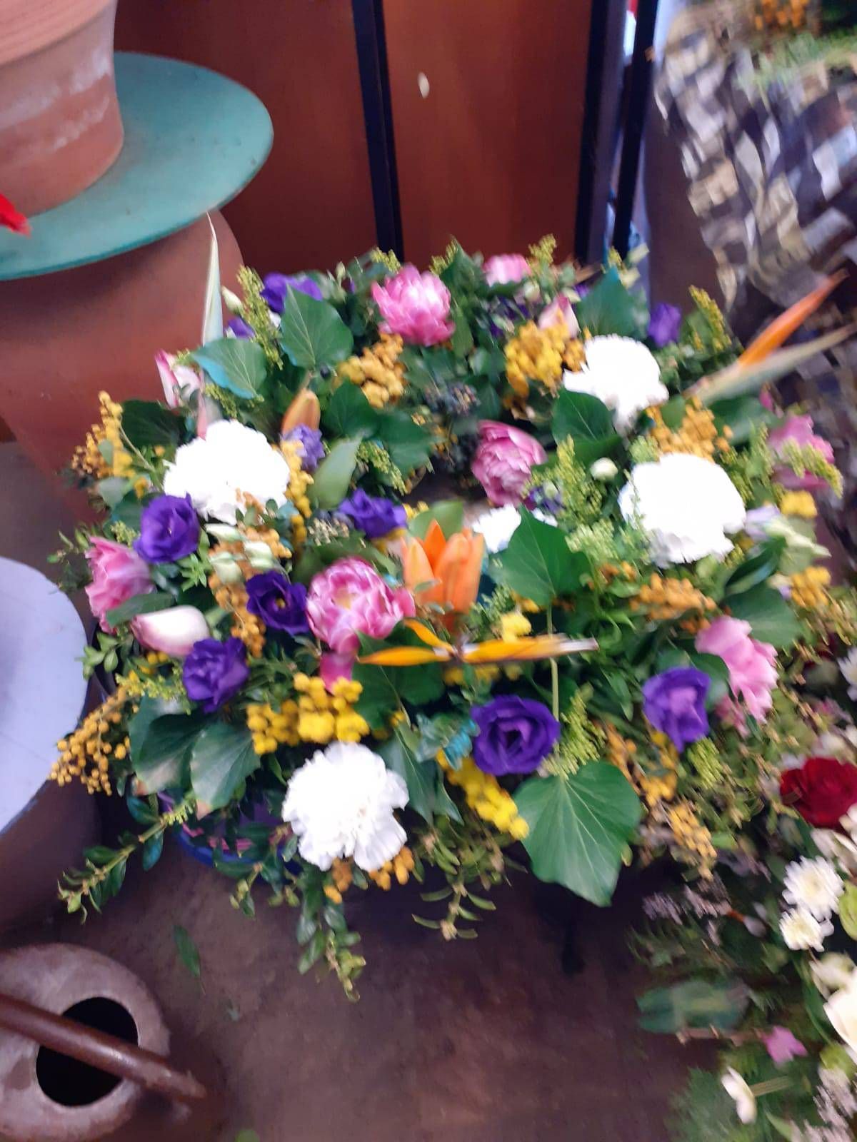 Blumenkranz mit rosa, lila und weißen Blüten, akzentuiert durch gelbes und grünes Laub.