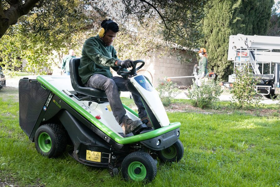 Un membre de Plagnol Espace vert en train de tondre la pelouse avec un tracteur-tondeuse
