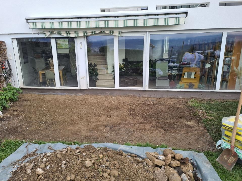 Schaufenster aus Glas mit davorliegendem Erdhof und Steineinfassung