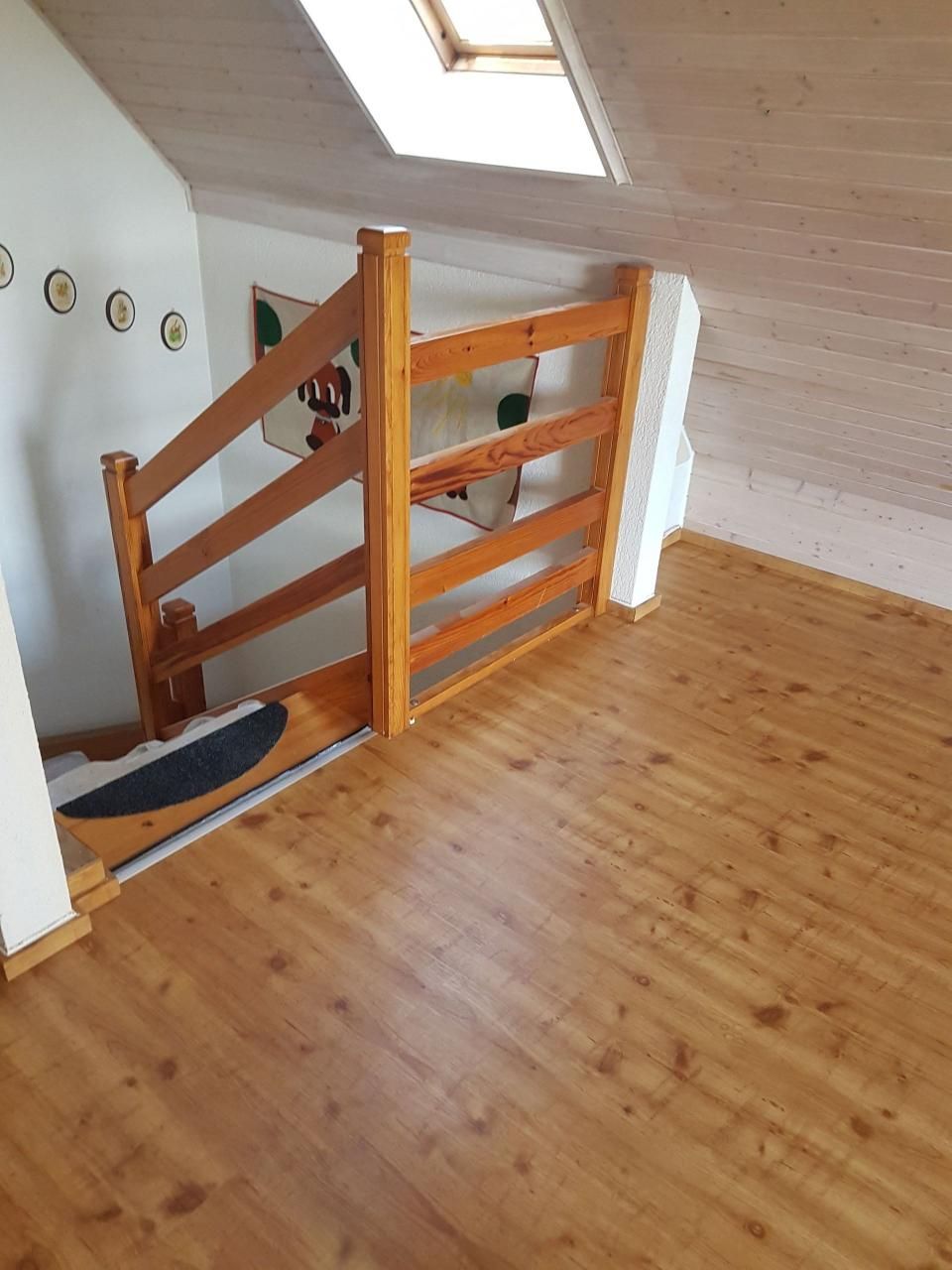 Treppenabsatz mit Holzgeländer, Oberlicht und hellem Holzboden in einem Dachgeschossflur