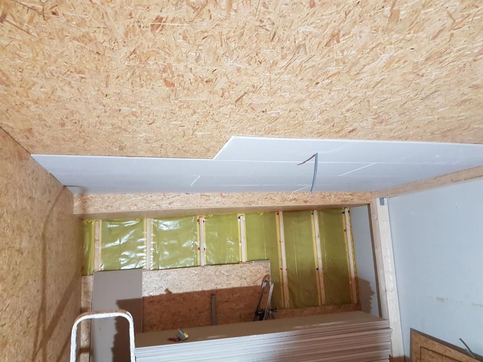 Innenbereich wird renoviert; Wände sind isoliert, die Decke besteht aus OSB-Platten und die Rahmenkonstruktion um ein offenes Treppenhaus ist sichtbar.