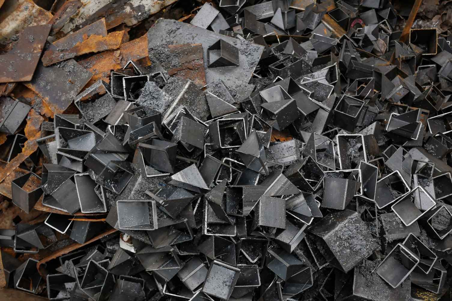 Montón de trozos y fragmentos de metal negro y color óxido apilados juntos