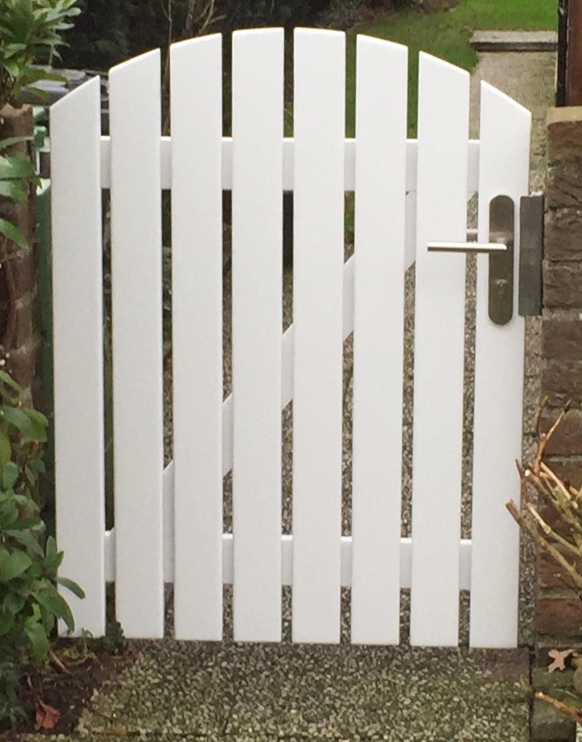 Weißes Lattentor mit gebogener Oberseite und silbernem Griff.