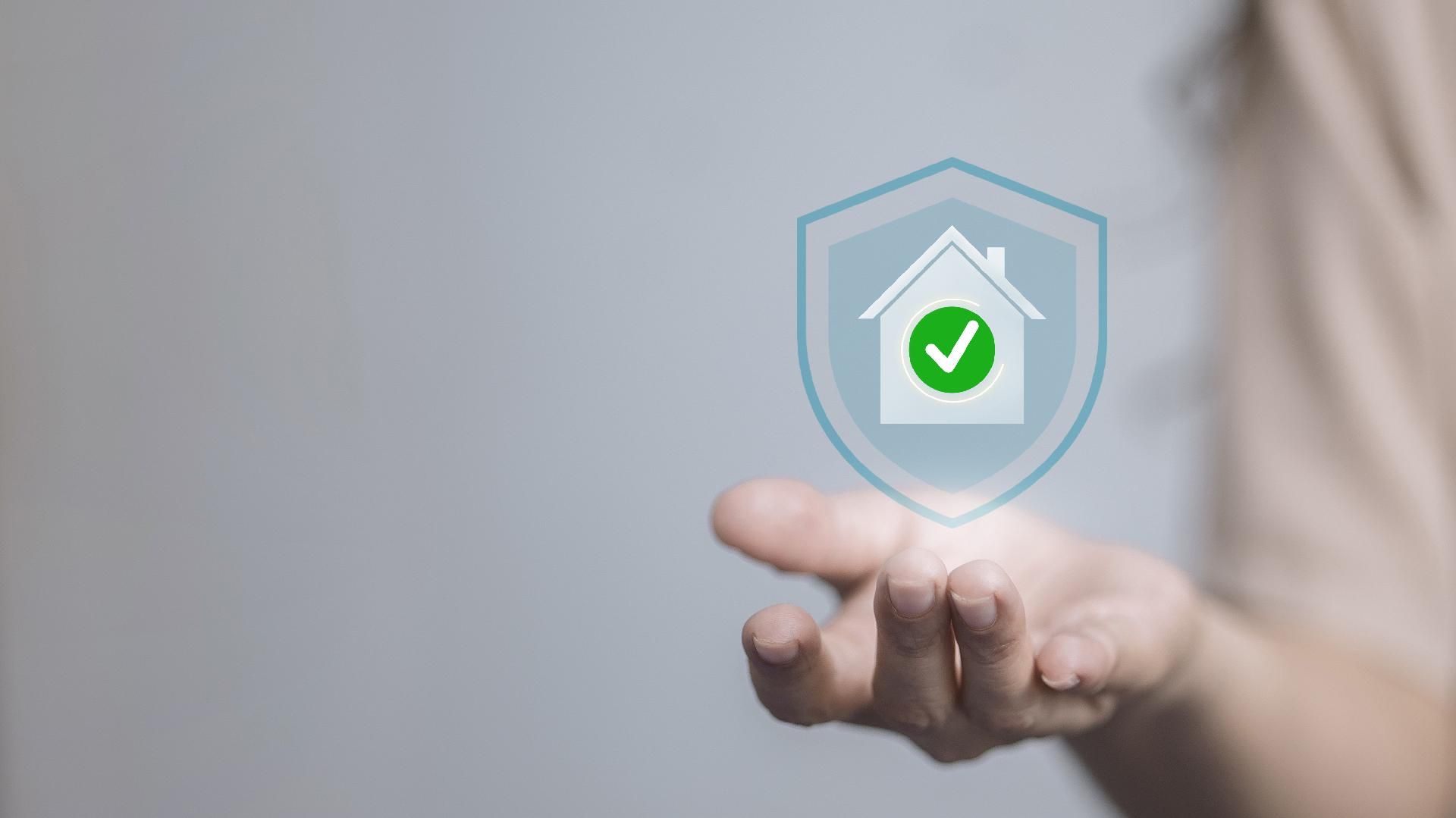 Hand hält symbolisches Haus mit grünem Haken