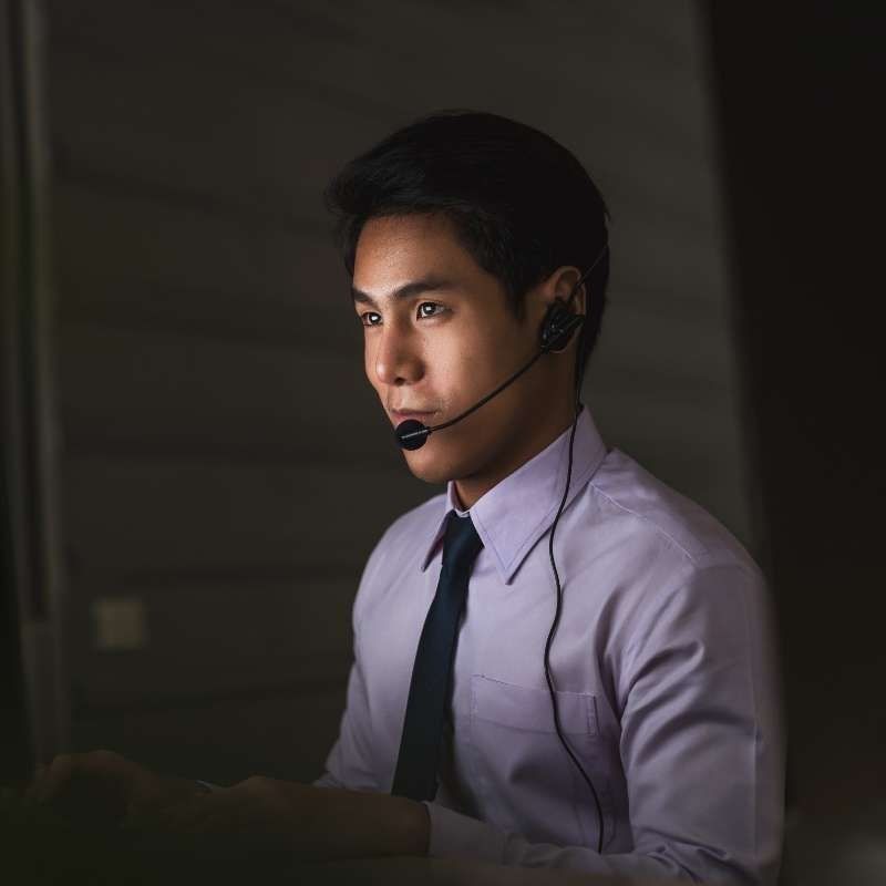 Un hombre que lleva unos auriculares está sentado delante de una computadora.