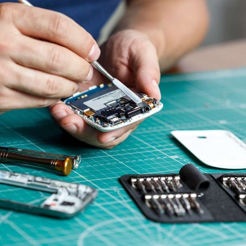 Un hombre está arreglando un teléfono celular con un destornillador.