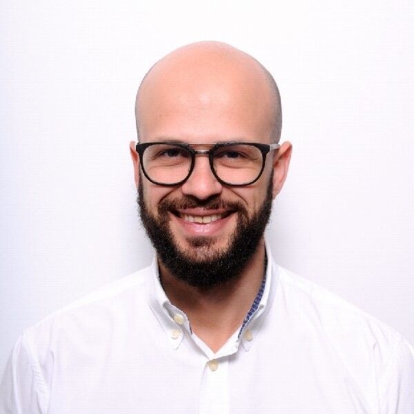A bald man with a beard wearing glasses and a white shirt
