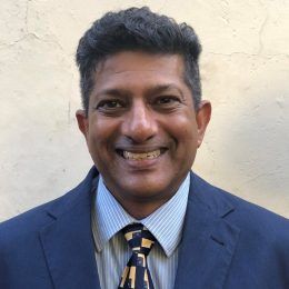 A man in a suit and tie is smiling for the camera.