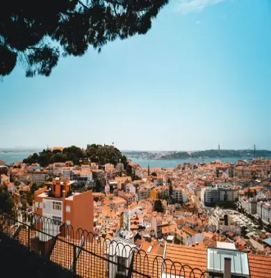 A view of a city from a hill with a fence in the foreground.