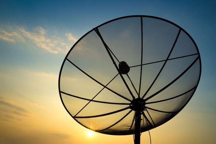 Antena parabólica recortada contra un cielo colorido al atardecer.