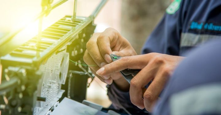 Manos de un técnico trabajando con componentes eléctricos. La luz del sol brilla desde la esquina superior izquierda.