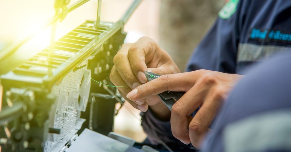 Persona con ropa de trabajo reparando una placa de circuito al aire libre. Primer plano con las manos enfocadas.