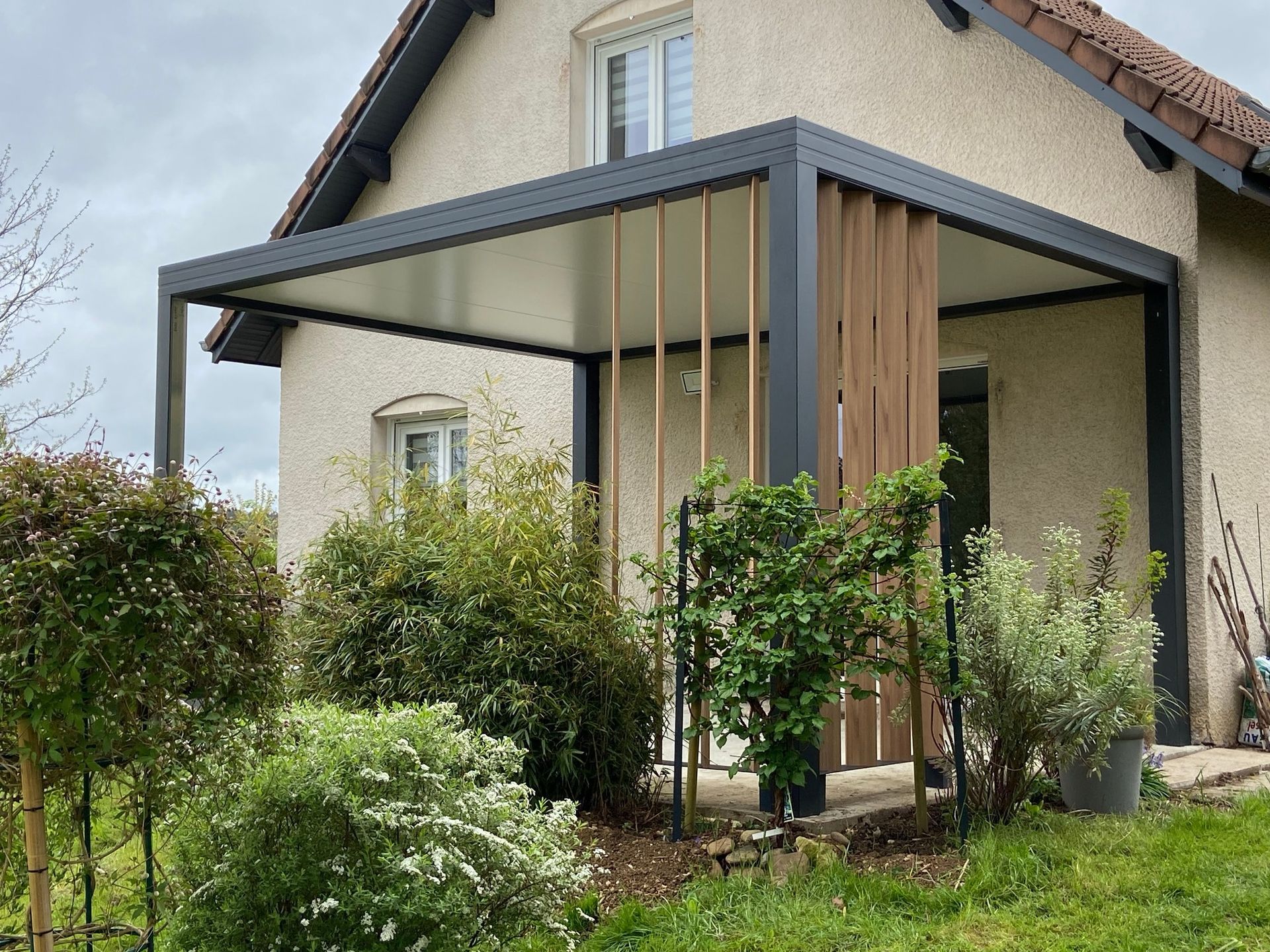 Pergola en aluminium noir couvrant une terrasse donnant sur un jardin