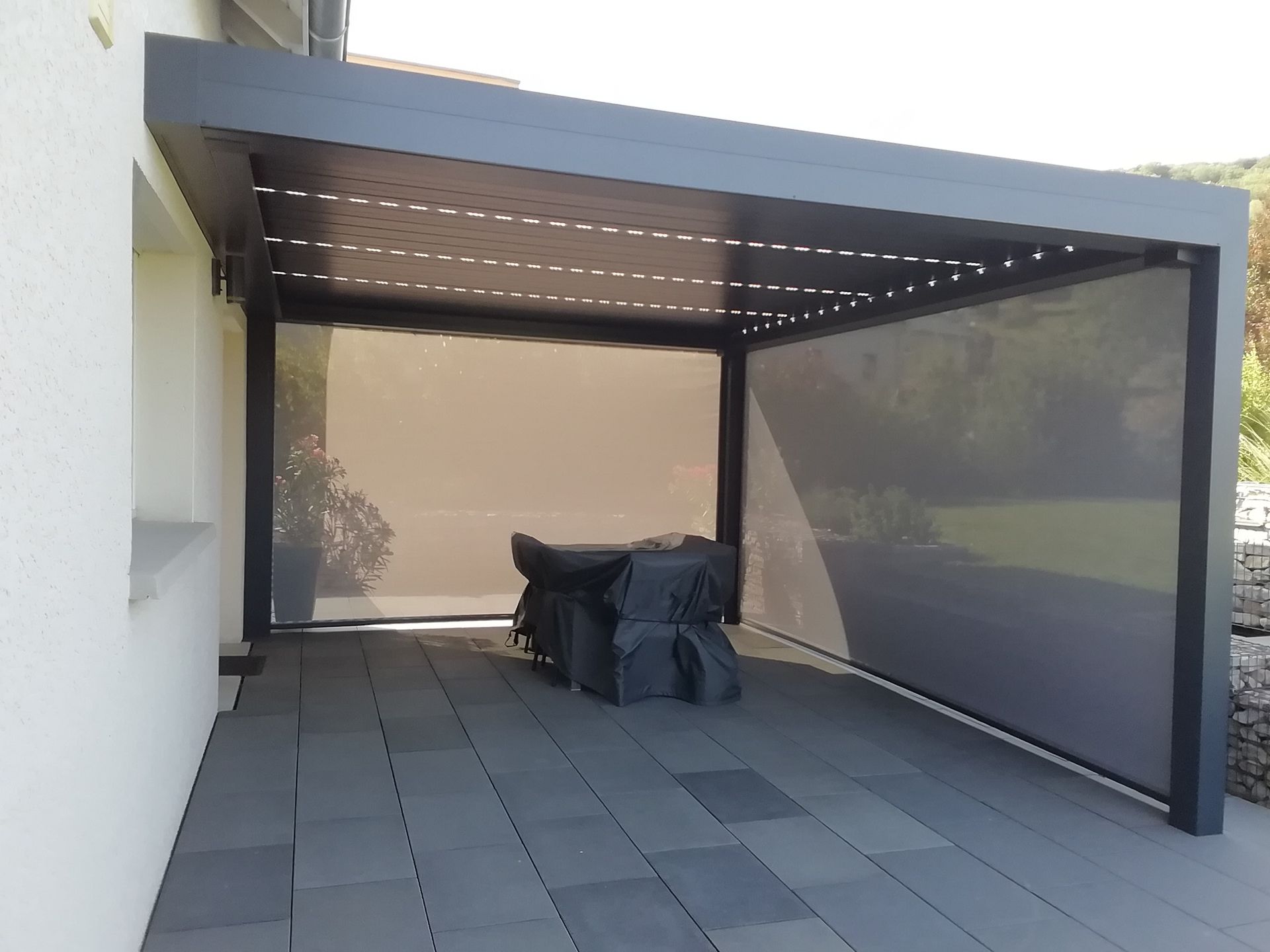Pergola à lames orientables aux stores légèrement baissés